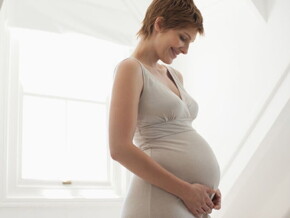 Femme enceinte tenant tendrement son ventre, illustrant l’importance de l’acide folique et des vitamines pendant la grossesse